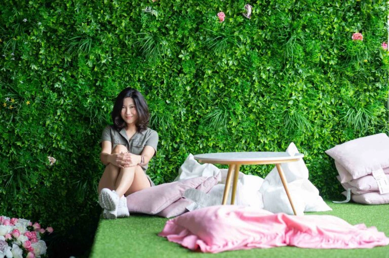 Jeune femme assise devant un mur végétal, jardin vertical