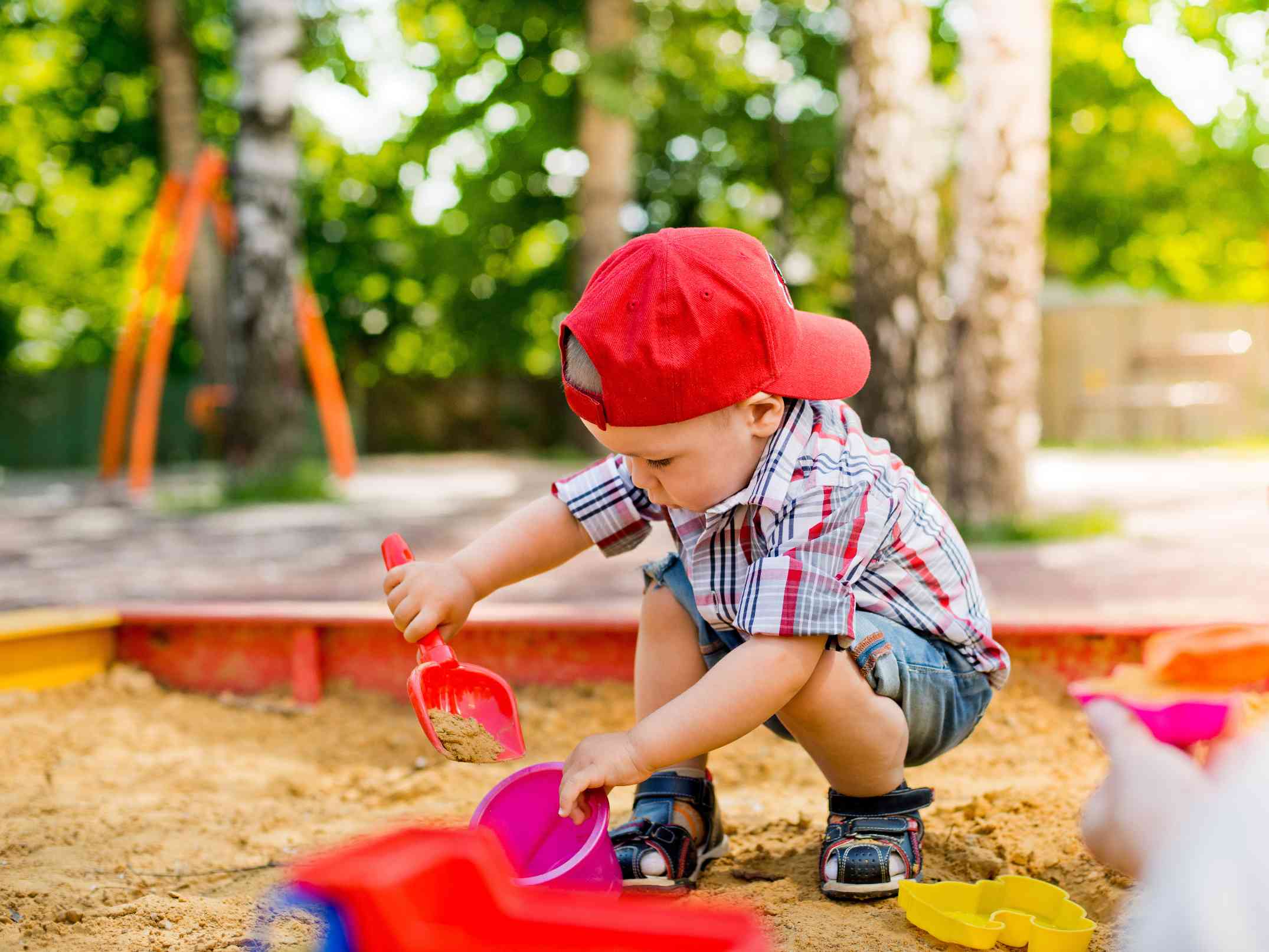 Enfant jouant dans un bac à sable aménagé dans la cour d'une maison