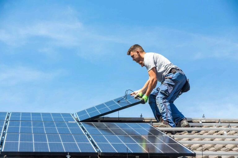 Deux ouvriers déposent des panneaux photovoltaïques sur le toit d'une maison