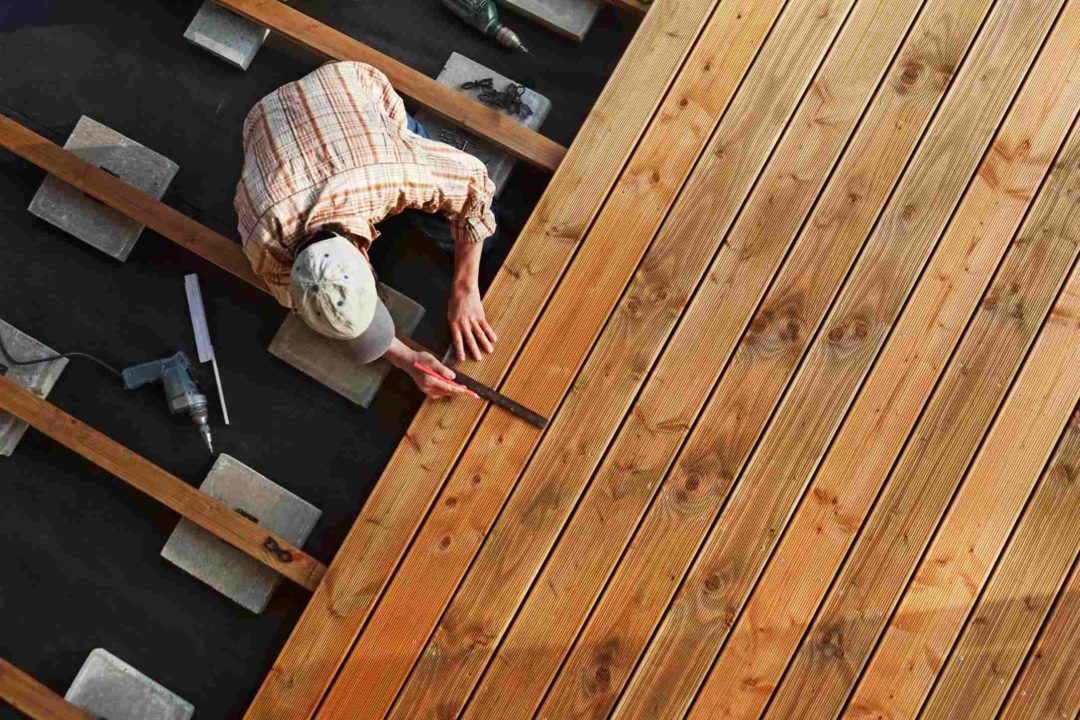 Un artisan construit une terrasse en bois dans un jardin