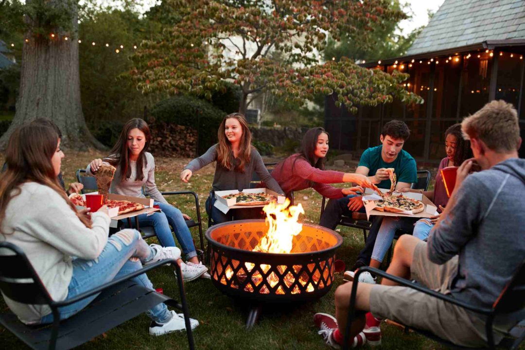 Une bande de jeunes amis réunis autour d'un brasero pour manger une pizza