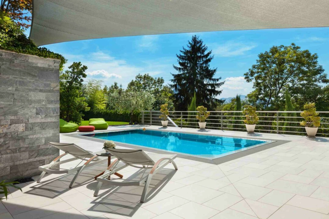 Belle piscine aménagée sur la terrasse d'une belle maison avec grand jardin