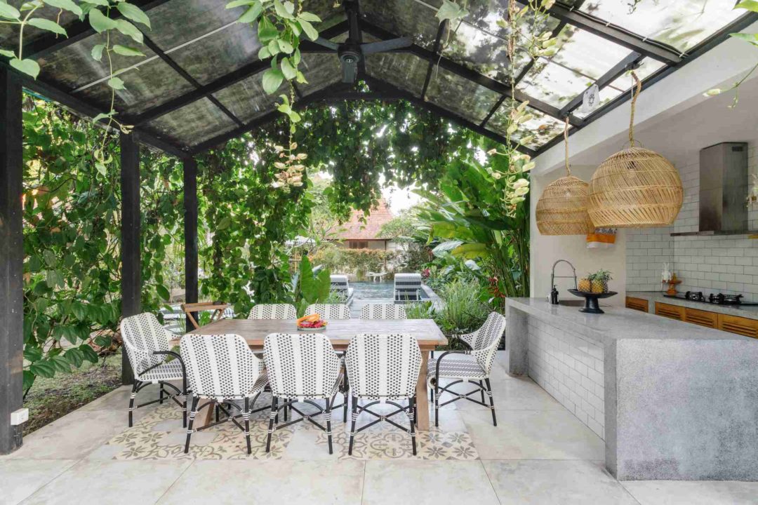 Une belle cuisine d'été installée dans un jardin paysager avec piscine en fond