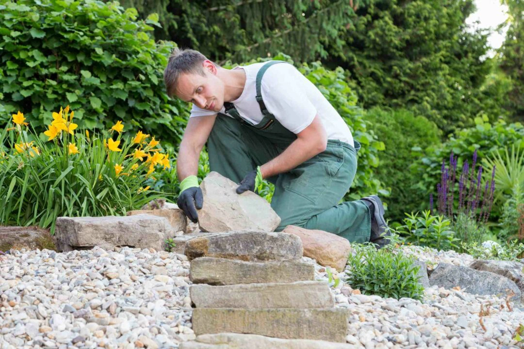 un jardinier paysagiste réalise un escalier avec des pierres naturelles dans un jardin privé