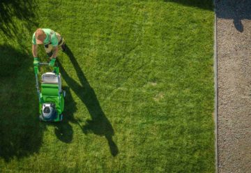 Un jardien passe la tondeuse sur une pelouse dans un jardin particulier