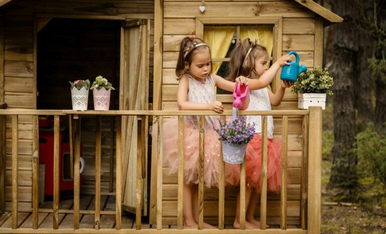 Deux petites filles jourent devant une cabane en bois dans un jardin