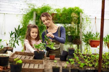 Une mère et sa fille jardinent dans une serre