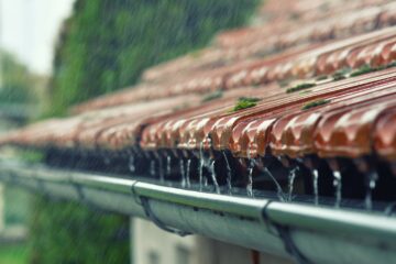 Le toit d'une maison et sa gouttière lors d'un jour de pluie
