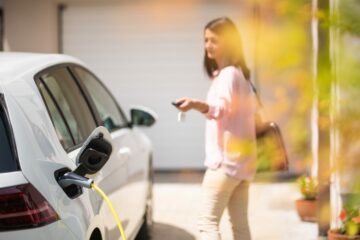 Une femme ferme sa voiture éléltrique en pleine recharge