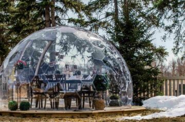 Un Garden Igloo ou abri bulle installé dans un jardin avec un espace déjeuner à l'intérieur