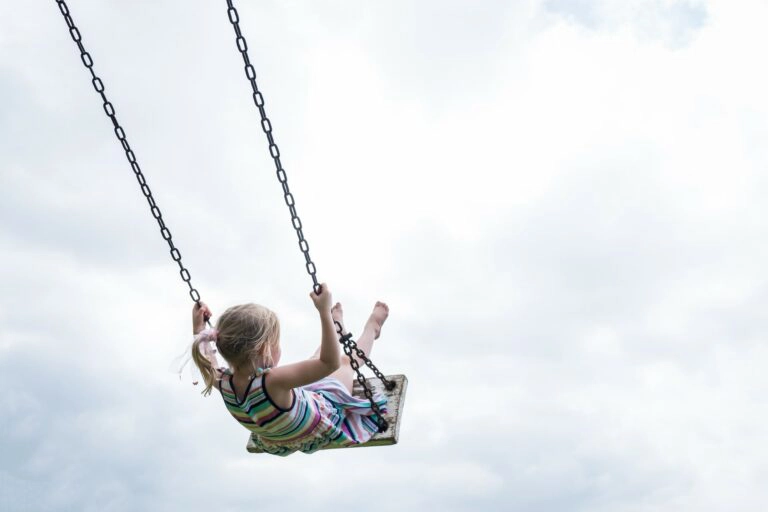Une fillette joue sur une balançoire dans une aire de jeux privée pour enfants