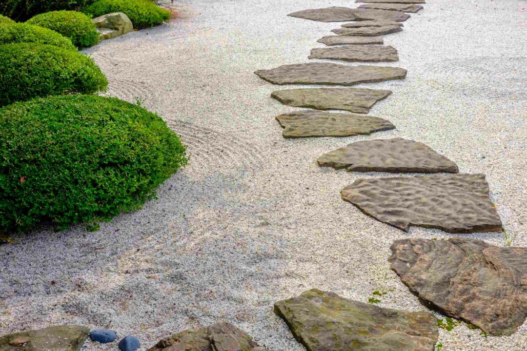 Un jardin type japonais avec du sable et des dalles de pierre