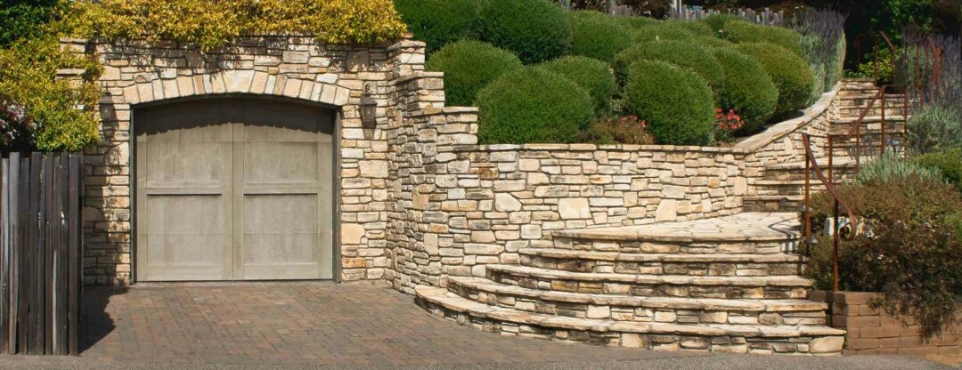 Une entrée de propriété avec un ecalier et un mur en pierres naturelles